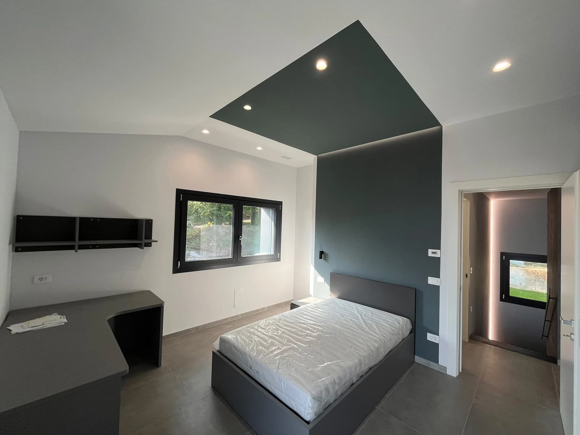La camera da letto rinnovata con parete colorata e faretti a soffitto