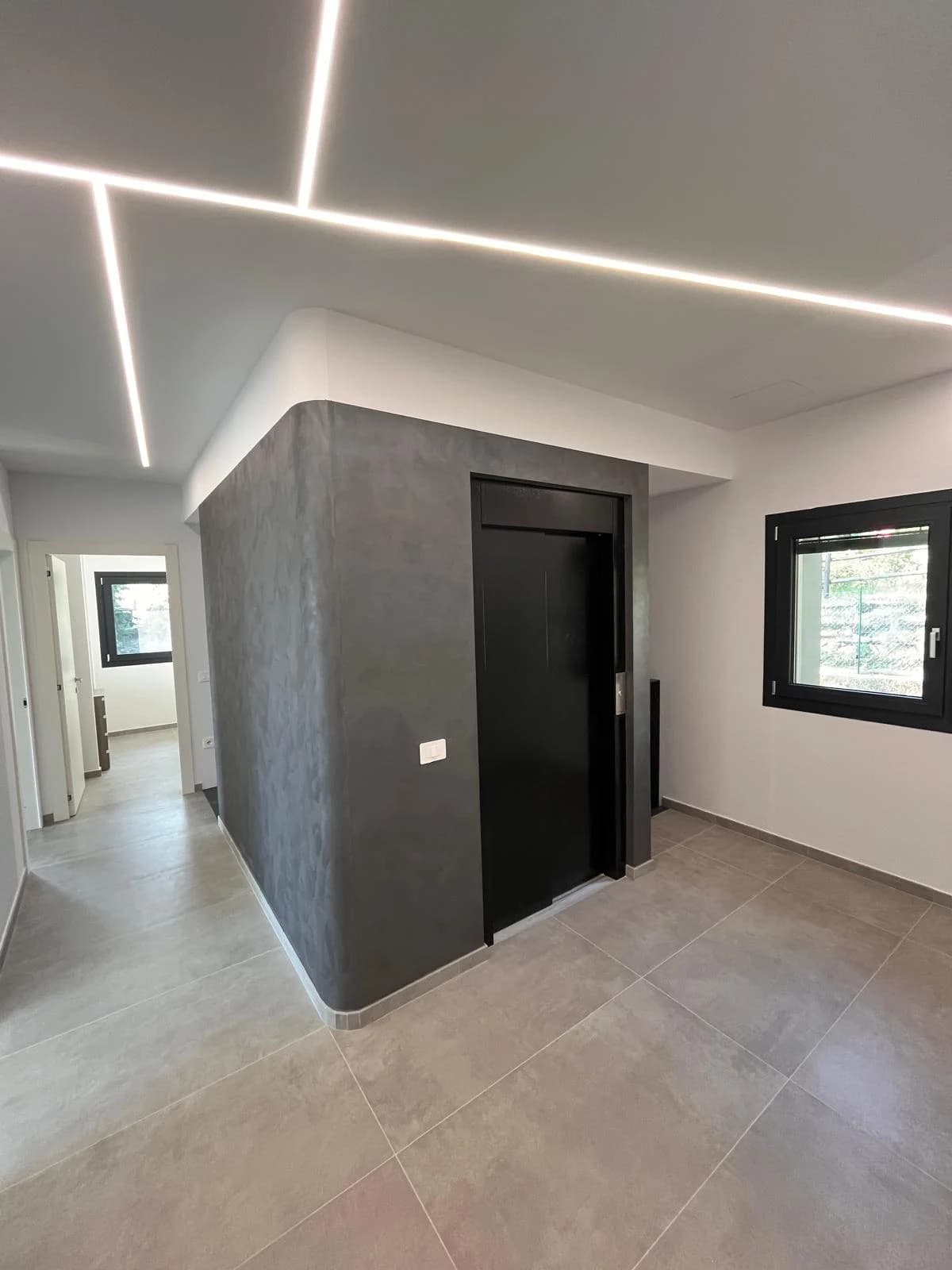 Il disimpegno con parete grigia e illuminazione lineare a soffitto