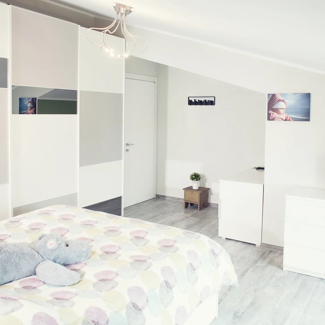 La camera da letto con armadio bianco e pavimento effetto legno