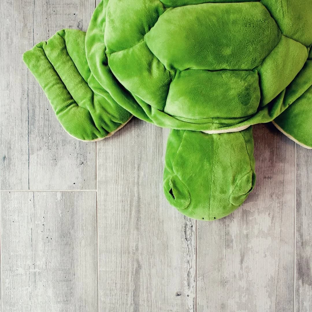 Dettaglio del pavimento effetto legno con un peluche verde
