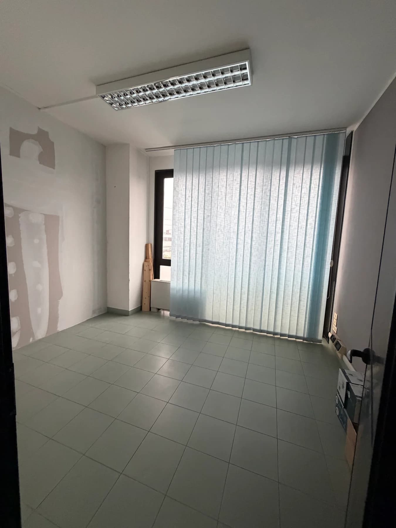 Studio Nidara prima della ristrutturazione: stanza con pareti da rifinire e ampia finestra