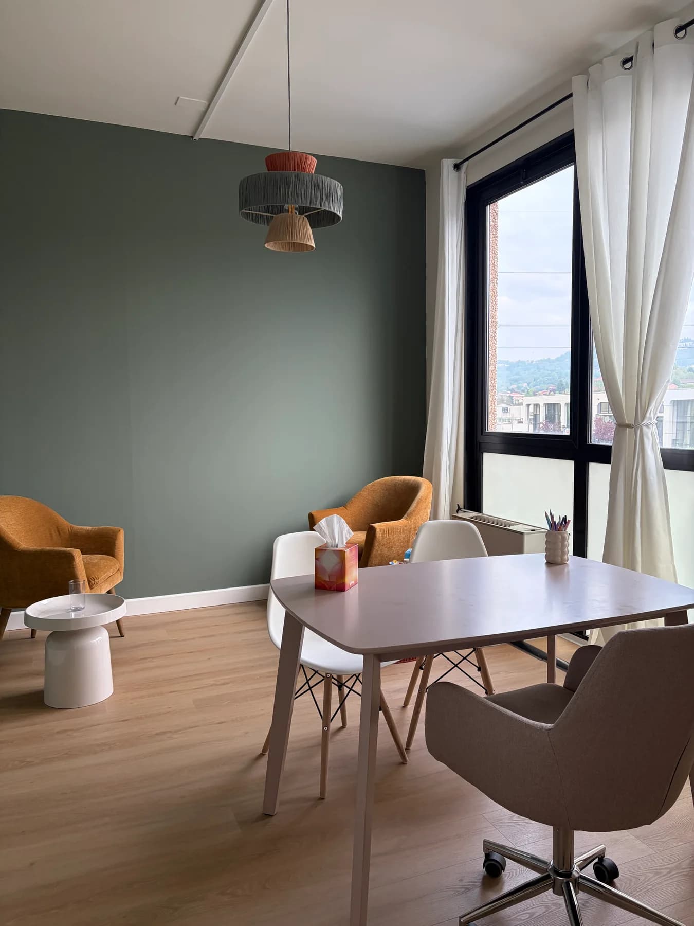 Lo studio con scrivania, sedute e parete verde dopo la ristrutturazione