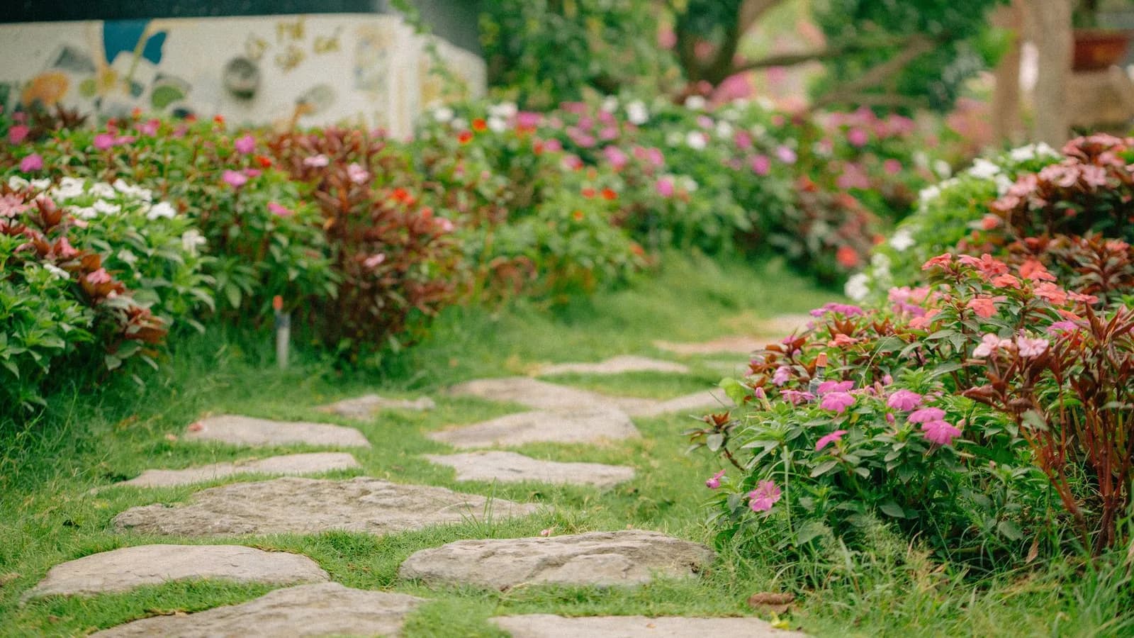 Sentiero in pietra tra aiuole fiorite e prato in un giardino